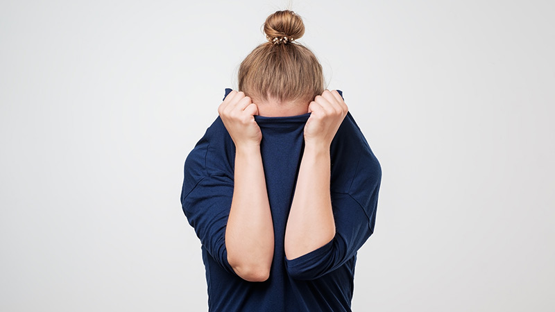 femme rentrant sa tête dans son pull